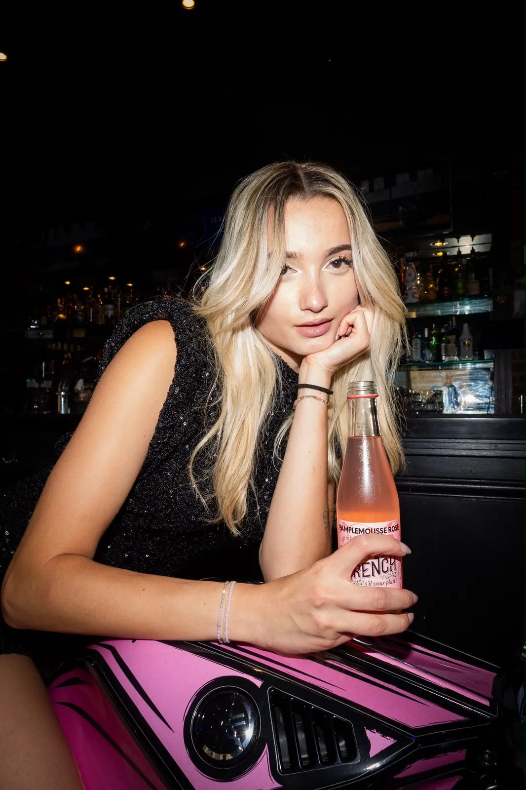 Portrait au bar, bouteille à la main, devant la moto rose